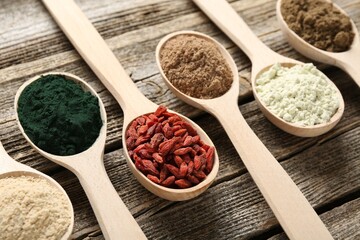 Different superfoods in spoons on wooden table, closeup