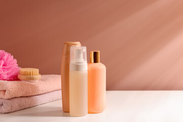 Different bathing products on white table near light brown wall. Space for text