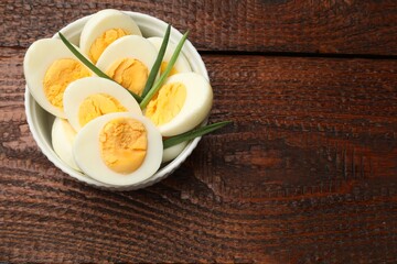 Boiled eggs and green onions on wooden table, top view. Space for text