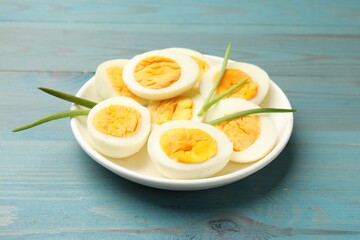 Halves of hard boiled eggs with green onions on blue wooden table