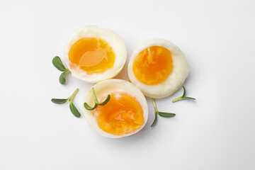 Soft boiled eggs with microgreens on white background, top view