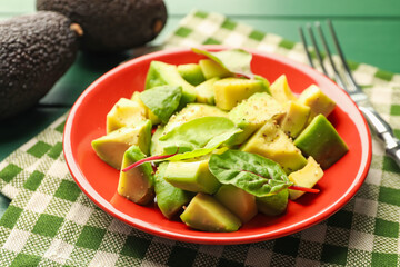 Tasty cut avocados with spinach and dressing on green wooden table, closeup