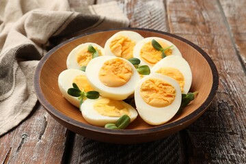 Hard boiled eggs with microgreens on wooden table, closeup
