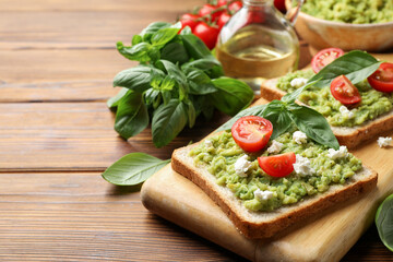 Delicious sandwiches with avocado, tomatoes, basil and cheese on wooden table, closeup