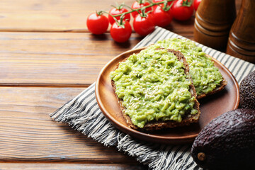 Delicious sandwiches with avocado, sesame seeds and tomatoes on wooden table, closeup. Space for text