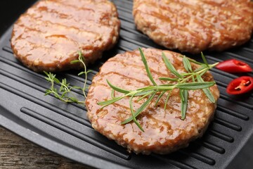 Delicious hamburger patties and spices in frying pan on table, closeup
