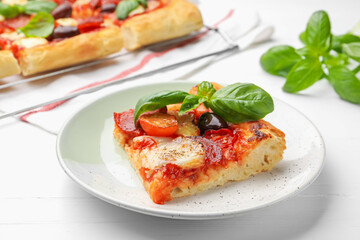 Piece of tasty homemade pizza on white wooden table, closeup