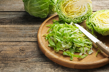 Cut fresh cabbage and knife on wooden table, closeup. Space for text