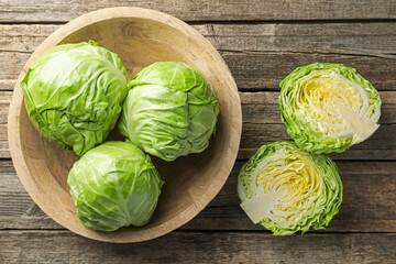 Fresh whole and cut cabbages on wooden table, flat lay