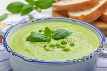 Tasty pea cream soup with basil served on table, closeup