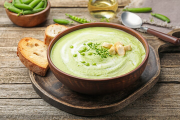 Tasty pea cream soup with croutons and thyme served on wooden table, closeup