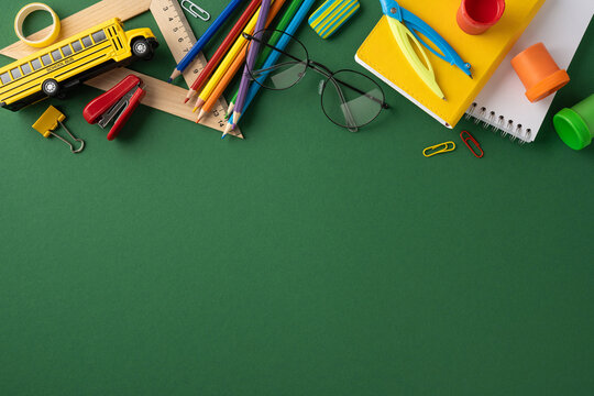Colorful school supplies like pencils, rulers, and notebooks displayed on a green surface