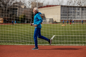 Fit senior runner running on stadium.