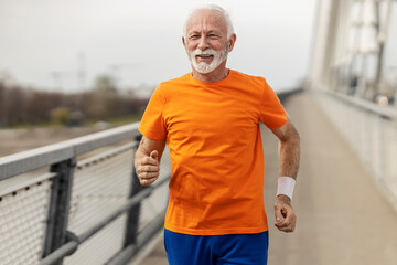Portrait of senior sportsman running on the bridge.
