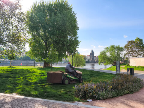 Prague, Czech republic - May 5, 2025: Gardener tesla mowing lawn in prague with vysehrad in background
