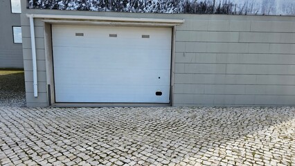 Closed White Garage Door on Modern Building With Cobblestone Pavement