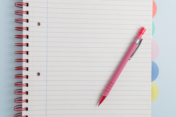 Open blank spiral bound lined notebook and pen