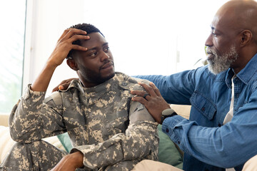 African American father and son sharing quiet moment in living room, with uniform, green pillow