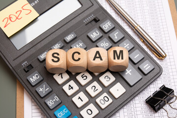 Wooden cubes with the word SCAM on calculator concept of financial fraud or deception.
