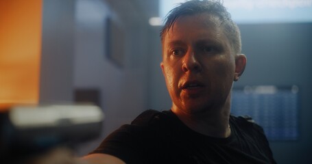 Close Up of Agent in Black Tactical Clothing Breathing Heavily, Aiming the Gun and Talking to the Enemy. Police Officer Attacking Unrecognizable Criminal in Dark Office Building. Action Movie Scene.