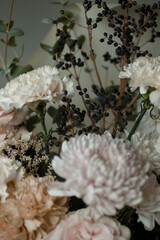 White carnation with black berries and soft pastel flowers. Elegant floral bouquet in natural light, perfect for background or design.