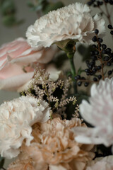 White carnation with black berries and soft pastel flowers. Elegant floral bouquet in natural light, perfect for background or design.