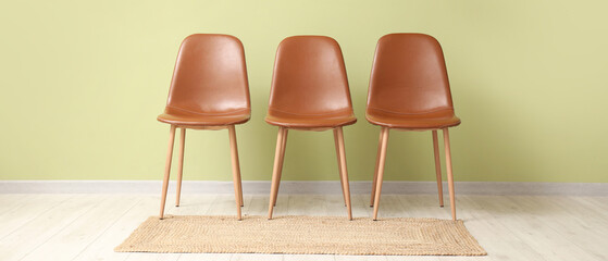Brown chairs and hanging lamp near green wall in room