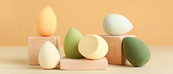 Fototapeta premium Decorative podiums with makeup sponges on beige background