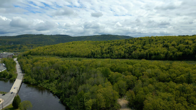 Aerial View of Maine Forest and River with Bridge and Road under Cloudy Sky