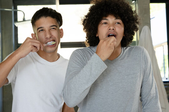 Brushing teeth Diverse father and son at modern bathroom sink, with foamy toothbrushes and towel