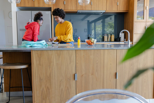 Chopping diverse family preparing meal in modern kitchen, with cutting board and sliced carrots