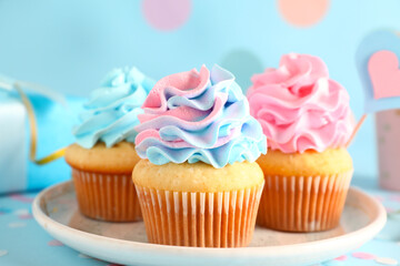 Plate with delicious cupcakes on blue background. Gender reveal party concept