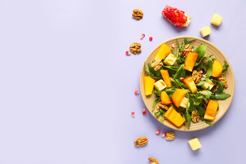 Plate of delicious salad with persimmon, pomegranate seeds and walnut on purple background
