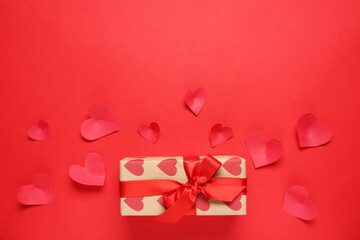 Composition with gift box and paper hearts on red background. Valentines Day celebration
