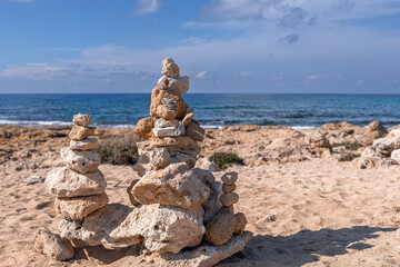 Balance stones stack tower close-up on Mediterranean sea background. Republic of Cyprus island coastline in sunny day
