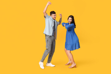 Fototapeta premium Happy young couple dancing on yellow background