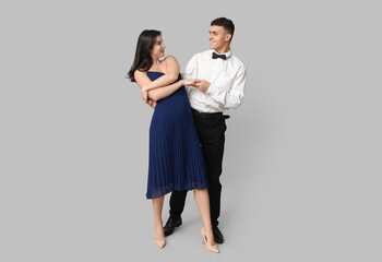 Beautiful young couple dancing on grey background