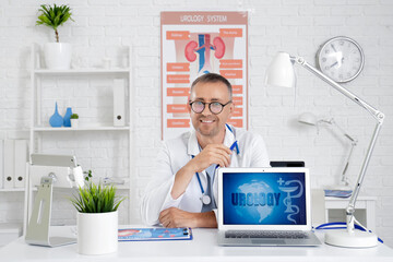 Male urologist with laptop sitting at table in clinic