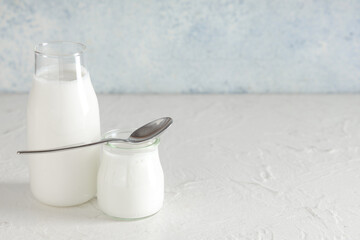 Bottle and jar of tasty yogurt on white background