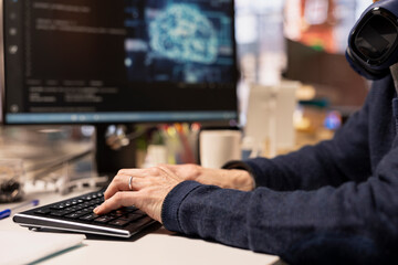 Software engineer in startup company office using computer to oversee artificial intelligence neural networks. Close up of IT professional using AI machine learning systems on PC
