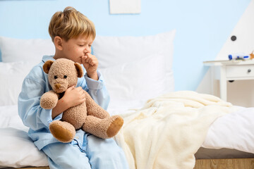 Little boy ill with chickenpox and toy bear coughing in bedroom