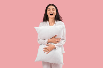 Fototapeta premium Beautiful young happy woman with pillow on pink background