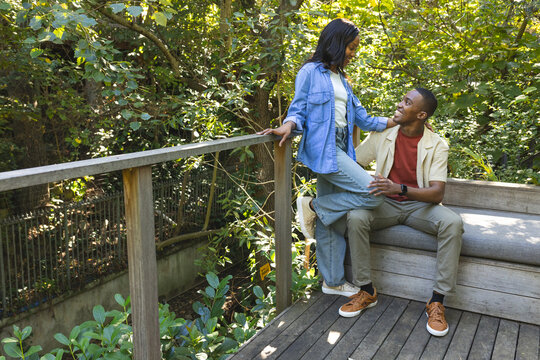 Leaning African American couple sharing moment on wooden deck, with bench and railing, copy space
