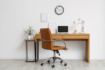 Clock on white wall near workplace in room