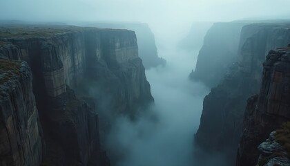Majestic foggy canyon with rock formations creating dramatic mysterious landscape. Misty clouds fill vale. Wilderness nature environment inspires adventure travel.