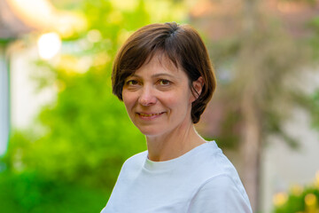 A 50-55 year old woman against a green backdrop, smiling at the camera.