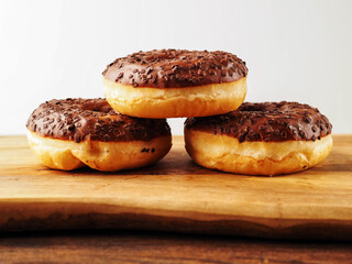 Sweet tasty chocolate donuts on wooden board. Popular desert and snack. Fine bakery product.