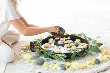 Woman with stones, flowers and candles meditating at home