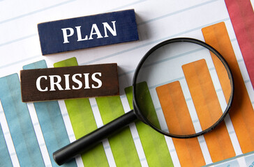 PLAN CRISIS - words on wooden blocks on the background of a graph and a magnifying glass