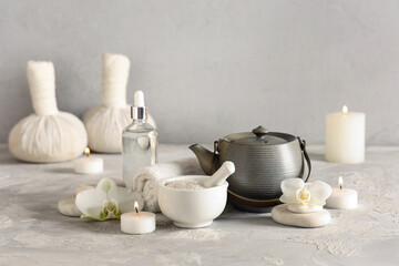 Composition with spa accessories, cosmetics, teapot and burning candles on light table